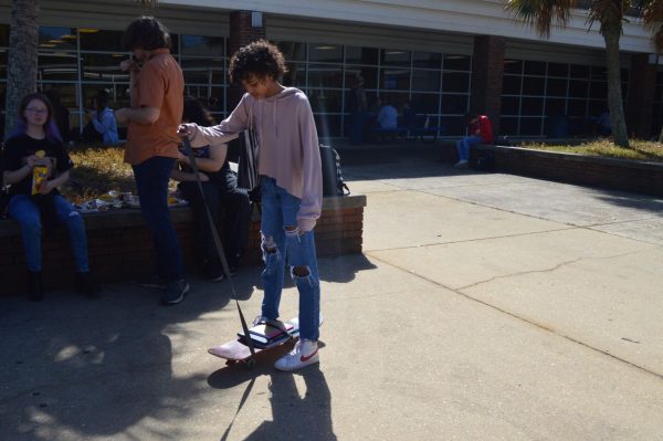 Balancing the books... Makayla Williams skateboards her books to class to support Red Ribbon Week theme of anything but a backpack. Williams practiced skating around before heading to class.