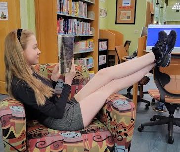 Relaxing read… Home-schooled sophomore Jill Cotten kicks back her feet as she reads in the Fairhope Public Library. After a day of volunteering, she wanted to unwind with a book.