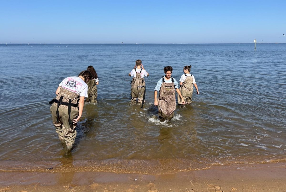 CLEANING THE COAST… Fairhope sophomores Landrey Parks and Emma Thomas, along with other volunteers, help test waders at the ACC on the north side of the Fairhope Municipal Pier. Parks and Thomas received service hours for Key Club.
