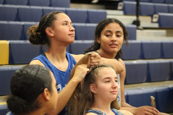 Weaving Friendships… Varsity Basketball player Lillian Moreno braids junior Lucia Jordan’s hair as sophomore Nylah Loukides watches before their match against the Roberstdale Bears on January 28. The day started at 4:30 with Junior Varsity, Girls Varsity and lastly Boys Varsity, while Senior Night activities happened during halftimes and after each Varsity game. “All my teammates are my friends and everything, so, it’s like—it’s really nice to be on a close team like this,” Loukides said.