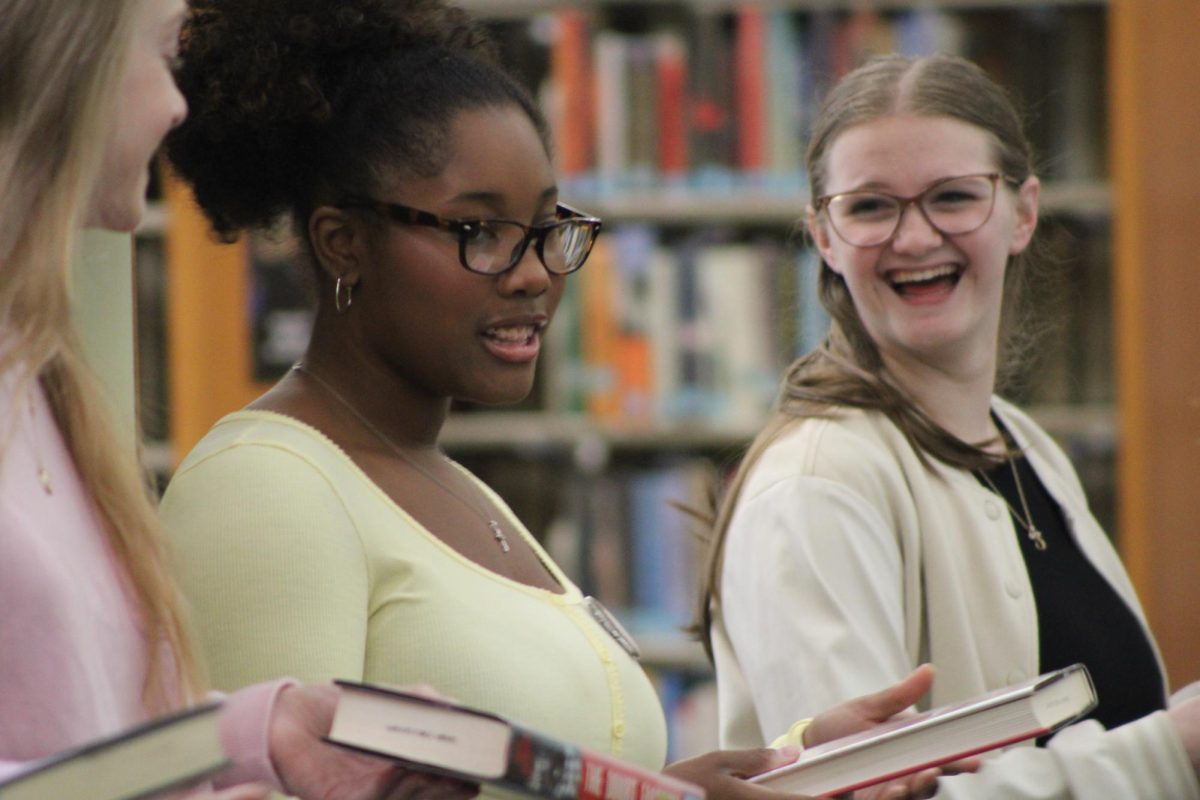 A new chapter… Teen volunteer Eleanor Boyer laughs at a joke teen volunteer Trinity Lewis tells as she passes a book down the line. Teen volunteer Jill Cotten, Lewis and Boyer stayed side-by-side throughout the event, enjoying each others’ company as they made book history.