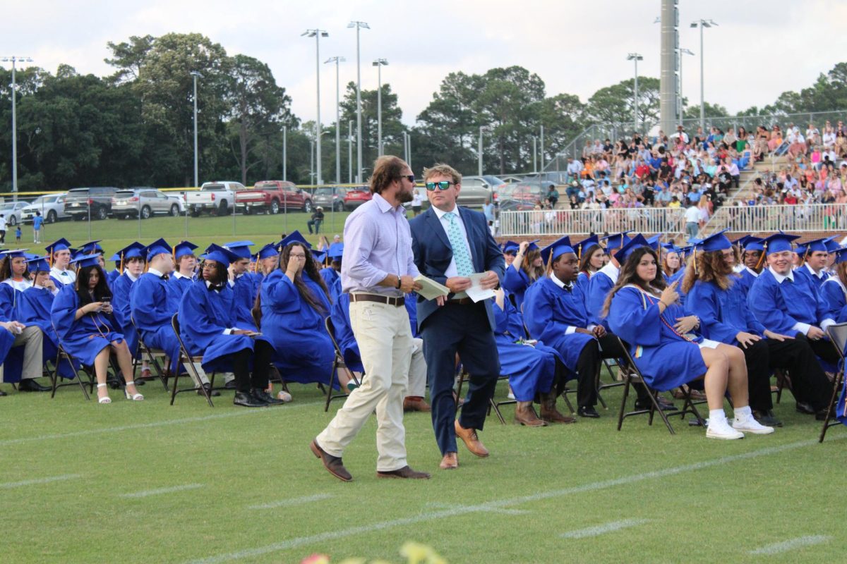 Assistant principal Josh Howell and Engineering teacher Cody Coleman direct seniors to their seats before graduation. Commencement exercises for Fairhope High School’s 354 graduating seniors took place on W.C. Majors Field at 7 p.m., May 20.