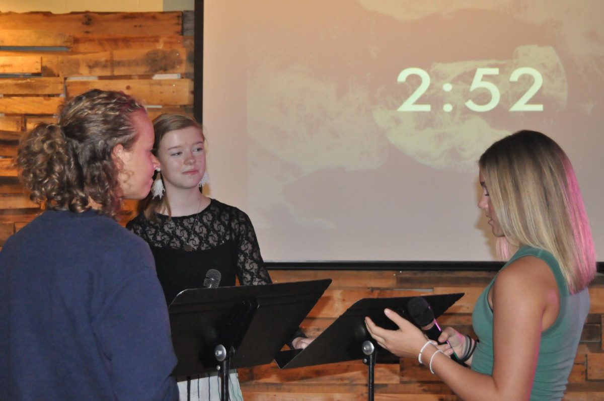 Meeting time... Freshman Rebecca Horn, junior Katelyn Kelley and eighth grader Elliiott Dorman, worship team leaders, discuss worship songs. Dorman, Horn and Kelley all led worship later that night.