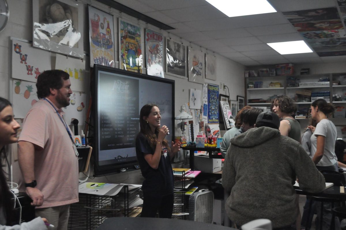 Attention everyone… Senior club president Emeryn Quint reminds classmates to sign their names on the sign-in sheet. By signing their name at every club meeting, members earn a half-hour credit to go towards their volunteer hours. (Kendall Kirchoff)